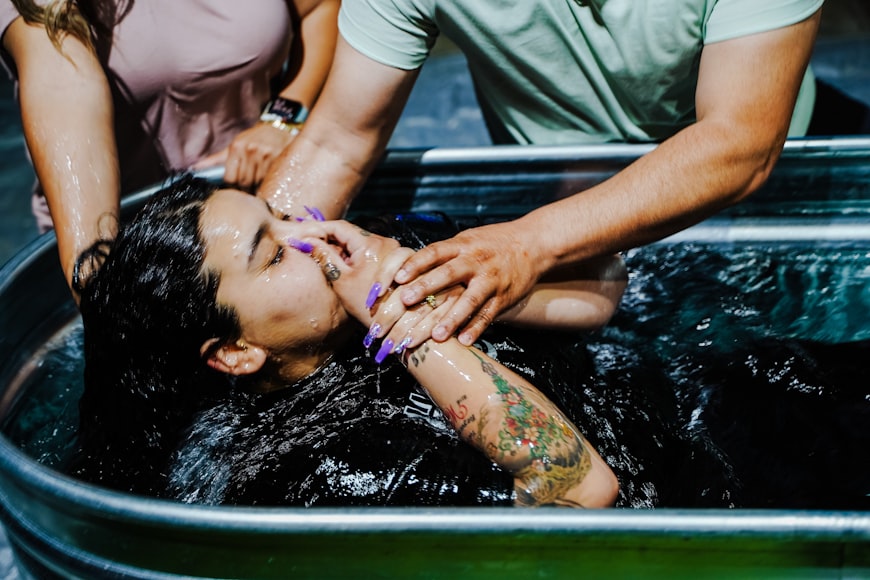 A woman being baptized by immersion, supported by two people in the water